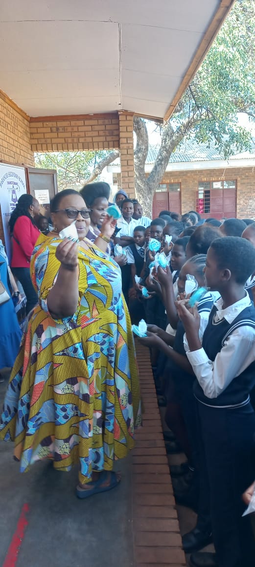 Municipal workers standing in front of pupils during a period poverty outreach holding Flo Angel Menstrual Cups