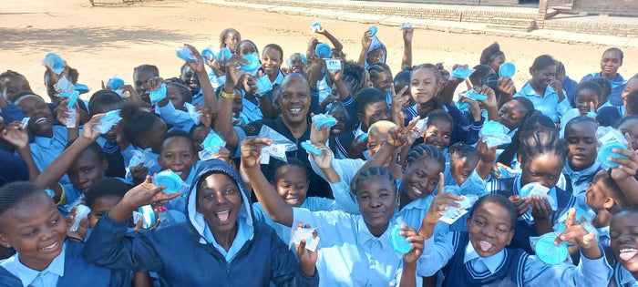 Happy students holding up their menstrual cups they received from a NPO.
