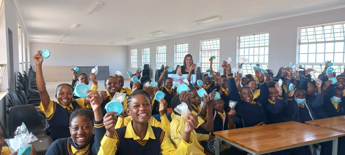 Classroom filled with smiling girls who received menstrual cups from a corporate social responsibility donation.